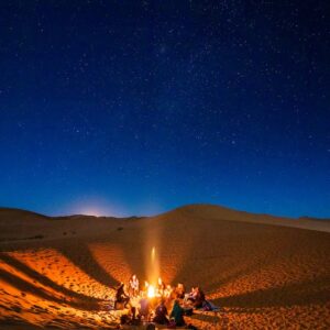 People Sitting in Front of Bonfire in Desert during Nighttime
