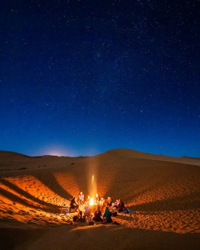 People Sitting in Front of Bonfire in Desert during Nighttime