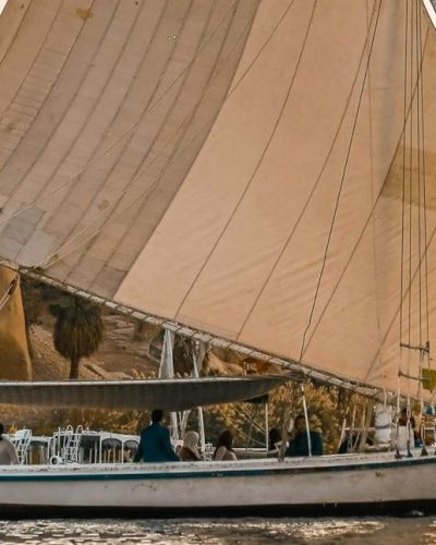 Scenic view of a traditional Egyptian felucca sailing at sunset on the Nile.