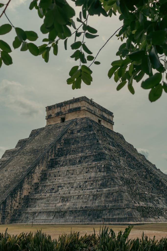 Explore the ancient structure of Chichen Itza under a cloudy sky.