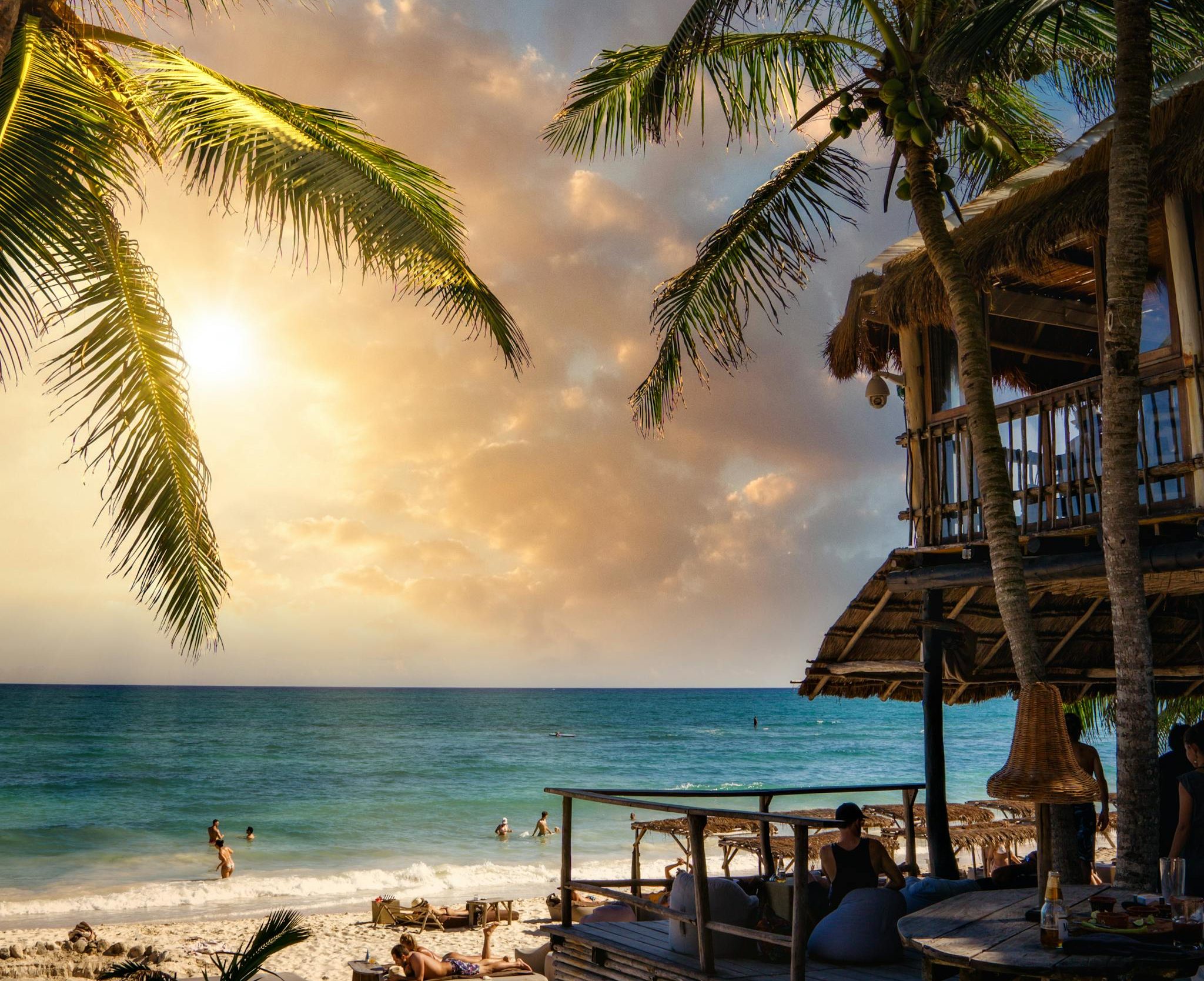 Stunning sunset view at Tulum Beach, Mexico, showcasing coconut palms and tranquil ocean.