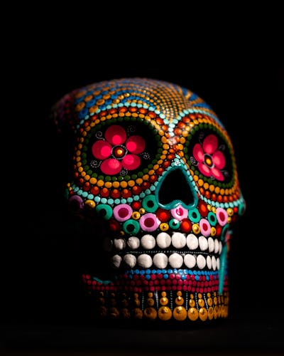 A vibrant and colorful sugar skull depicting Day of the Dead art with intricate designs on black background.