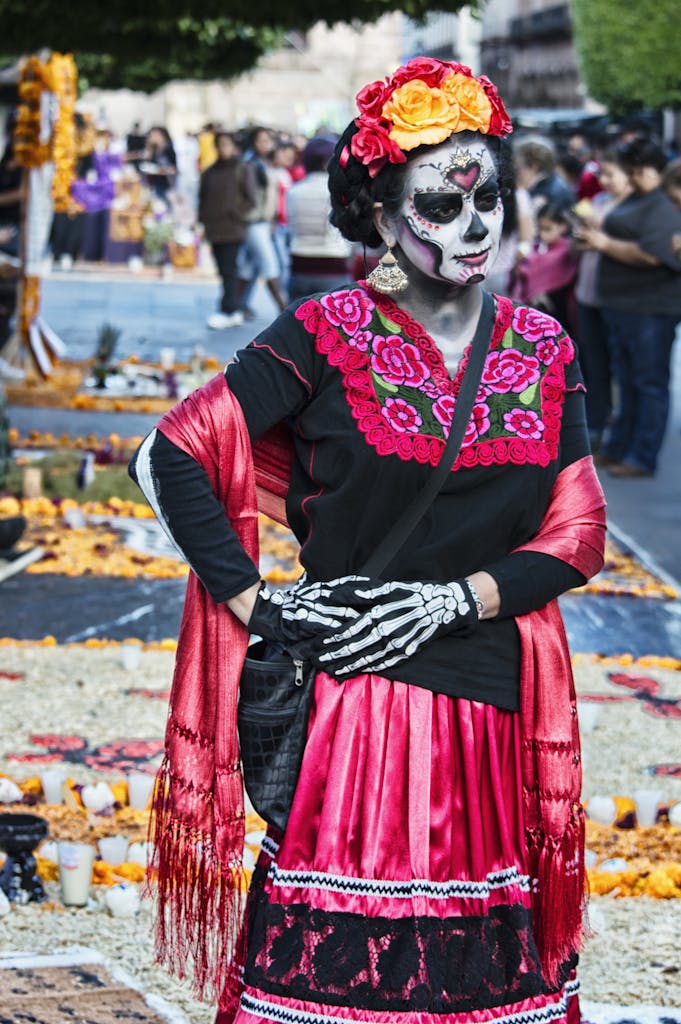 Woman in traditional Day of the Dead costume and face paint at a festive parade in Mexico City.